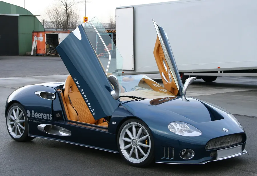 Spyker C8 Laviolette con puertas de mariposa abiertas frente a un trailer JDC-Trans