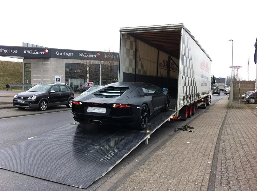 Lamborghini negro en carga sobre un camión JDC